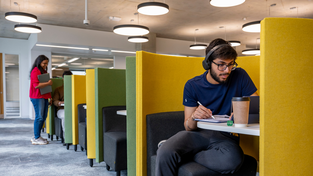 Male Southampton student working on a laptop with headphones