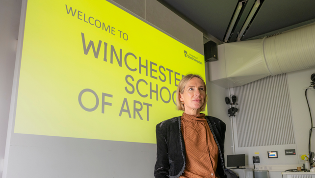 Southampton lecturer standing in front of projector that reads 'Welcome to Winchester School of Art'